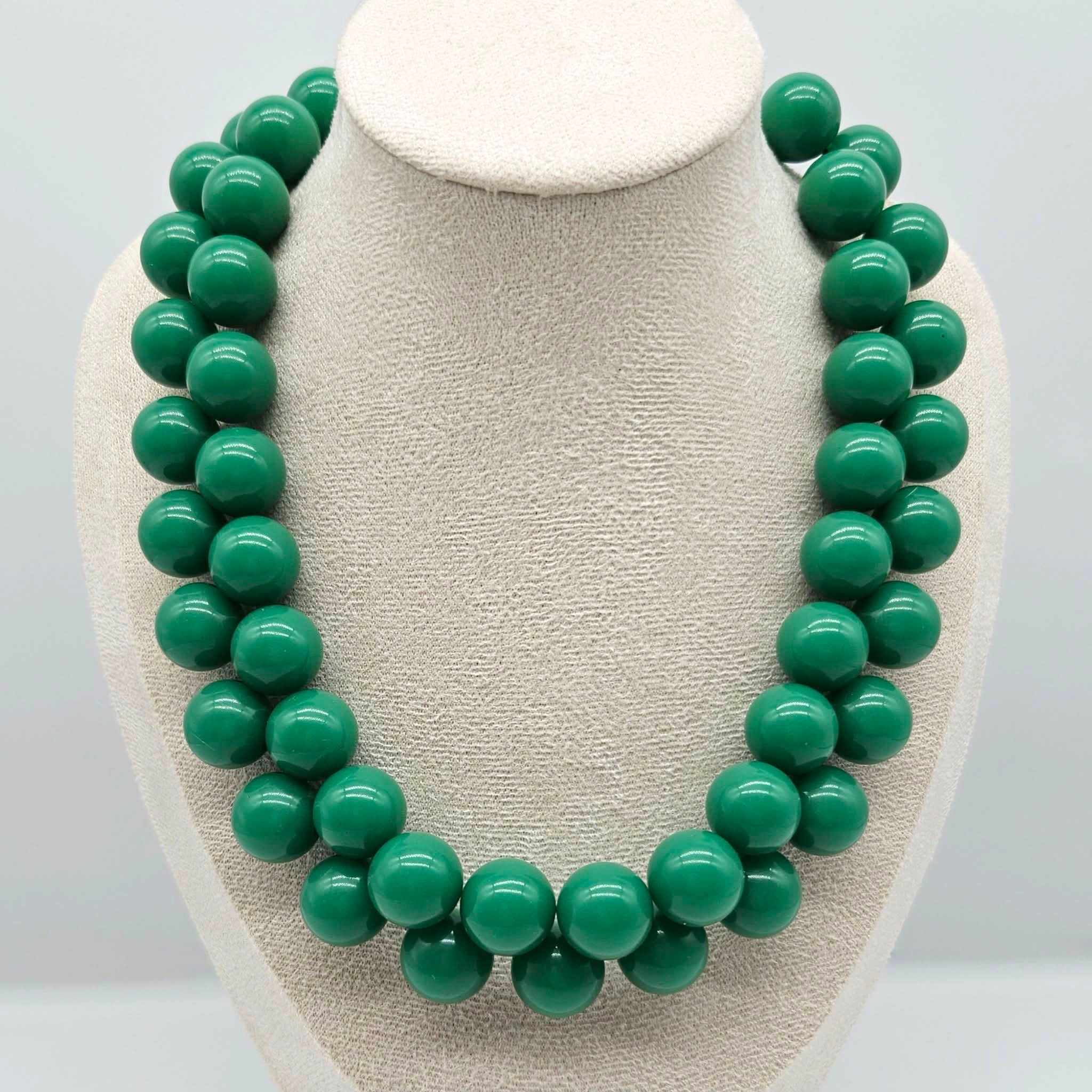 Opaque green beaded necklace on a bust.