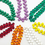 Multiple colorful beaded necklaces laid out in a circle on a white background.