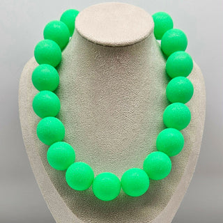 Necklace with green beads on a gray stand