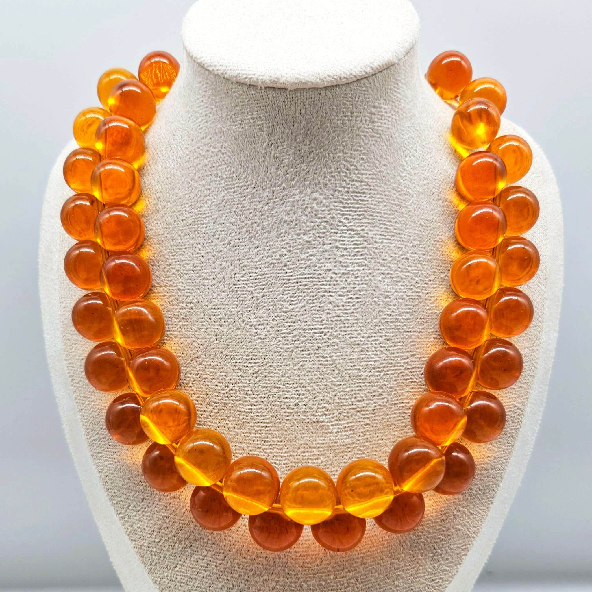 Orange cluster beaded necklace on a bust.