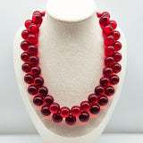 Red cluster beaded necklace on a bust.