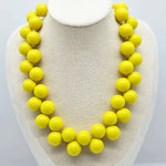 Yellow cluster beaded necklace on a bust.